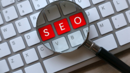 Magnifying glass signifying search concept over keyboard highlighting letters SEO in red
