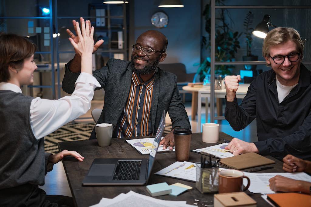 A group of people high-fiving in a business meeting, happy with the success of their campaign from an SEO agency Gold Coast