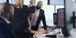 Photo of happy staff in an office giving each other high-fives