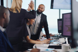 Photo of happy staff in an office giving each other high-fives